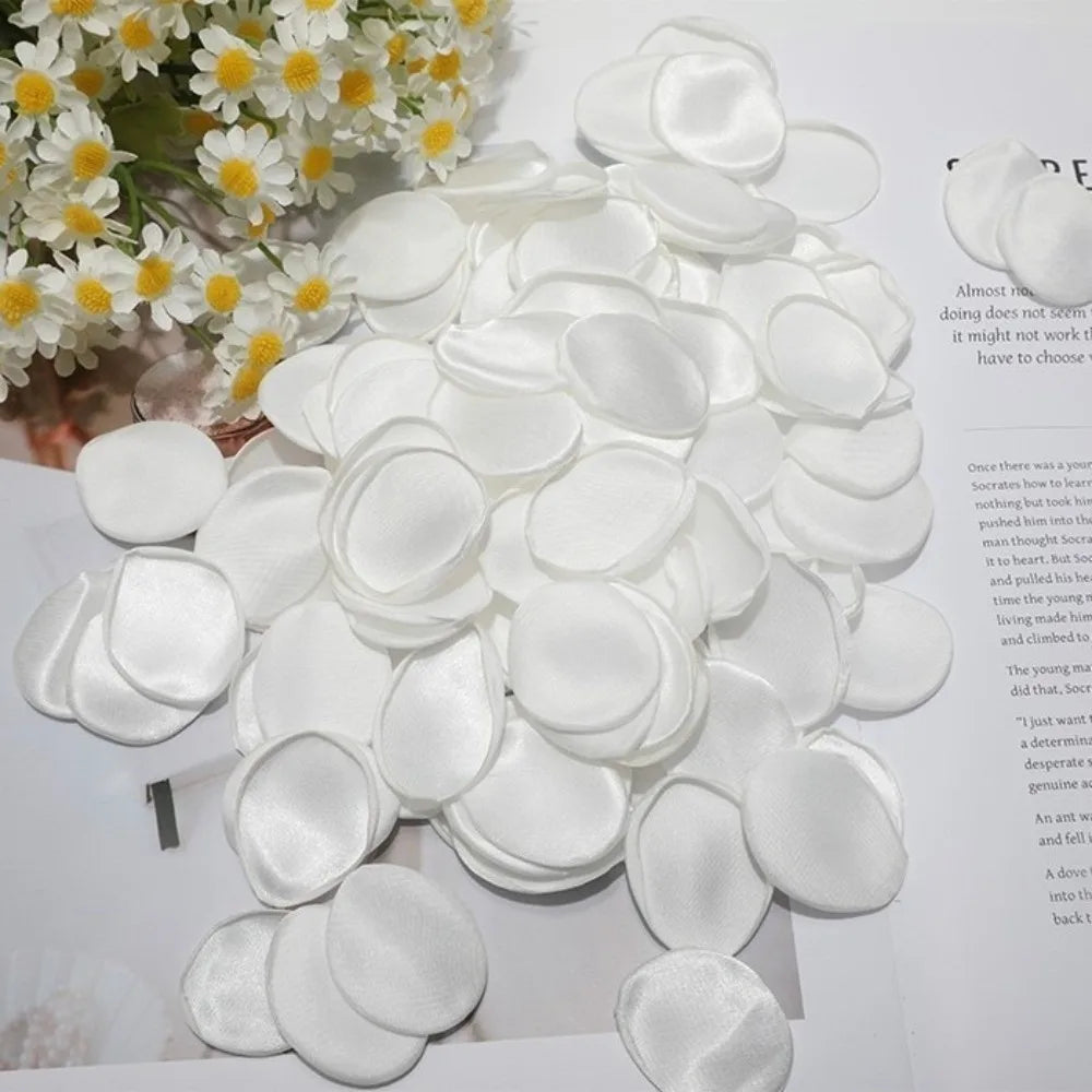 Un amas de pétales de roses de soie artificielle blanches disposés de manière décorative.