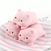 Three pink pig mochi squishy stress relief toys resting on a striped paper.