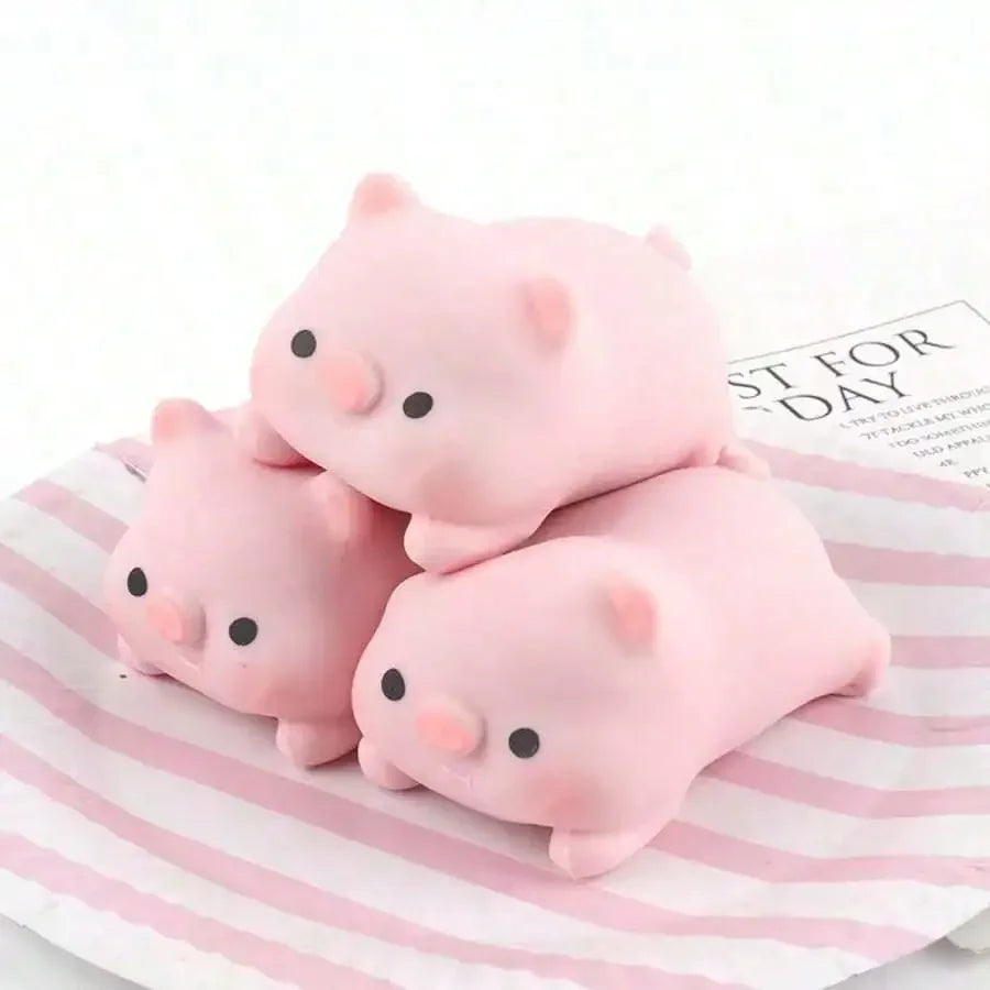 Three pink pig mochi squishy stress relief toys resting on a striped paper.