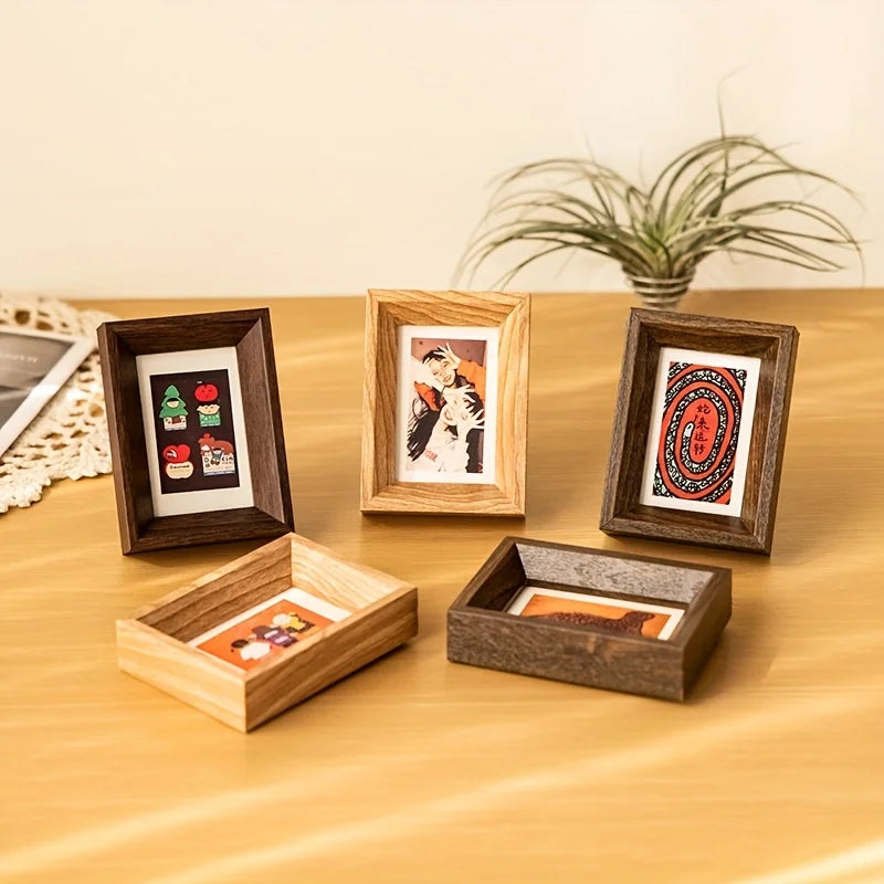 A collection of wooden photo frames and a potted plant displayed on a wooden surface.