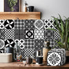 Black and white geometric tile wall stickers featuring floral and cross patterns on a wooden surface.