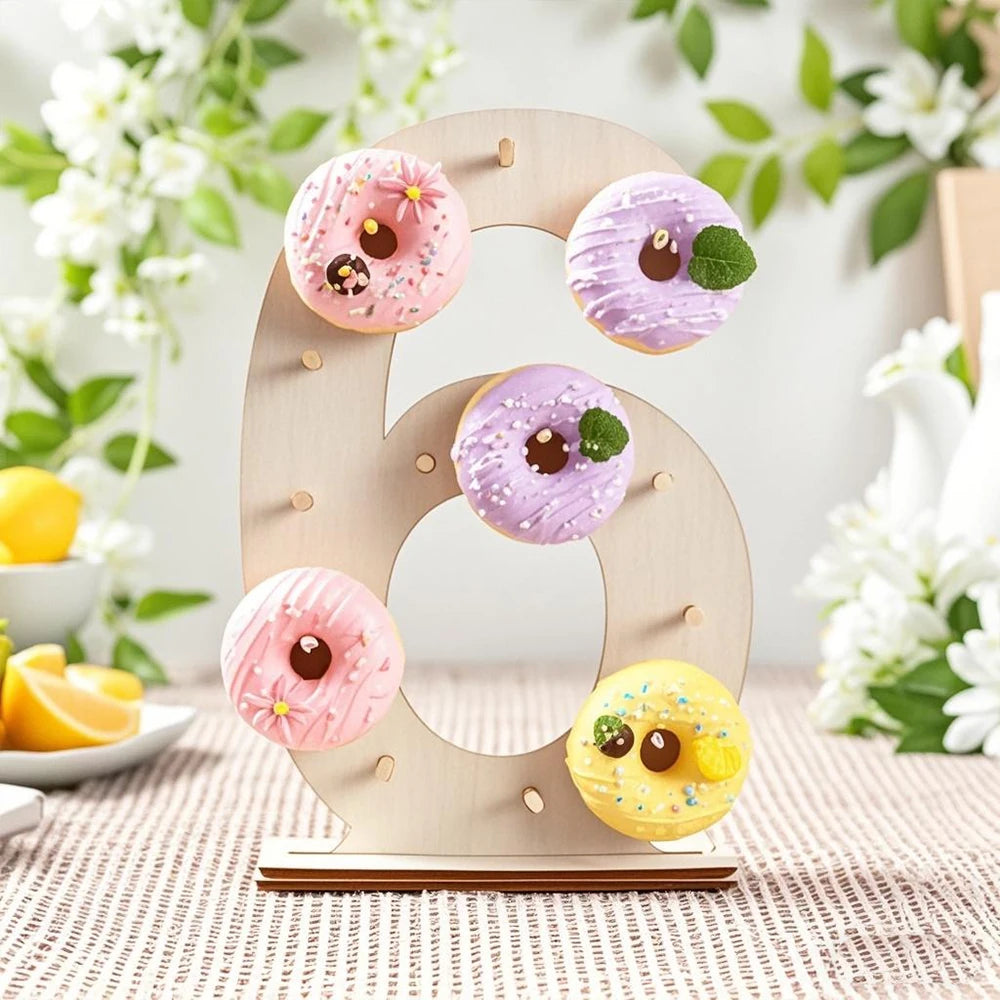A wooden number display stand shaped like the letter O holds various frosted donuts and a yellow donut.