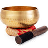 A handcrafted copper singing bowl resting on a wooden mallet.