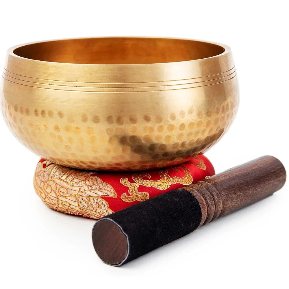A handcrafted copper singing bowl resting on a wooden mallet.