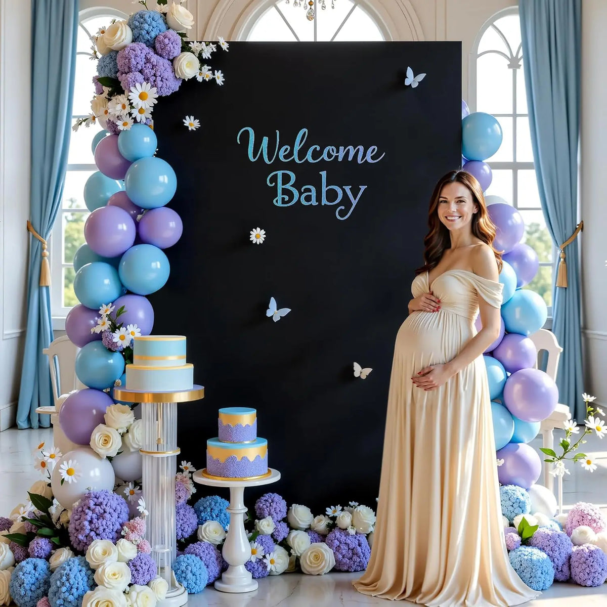 Foto de maternidad con una mujer en un vestido amarillo fluido frente a un fondo negro decorado con azul y...