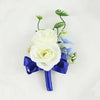 A boutonniere set featuring white roses and dusty blue silk flowers arranged on a dark blue ribbon.