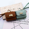 A pair of mini leather openable bags in brown and mint green colors resting on a white paper background.