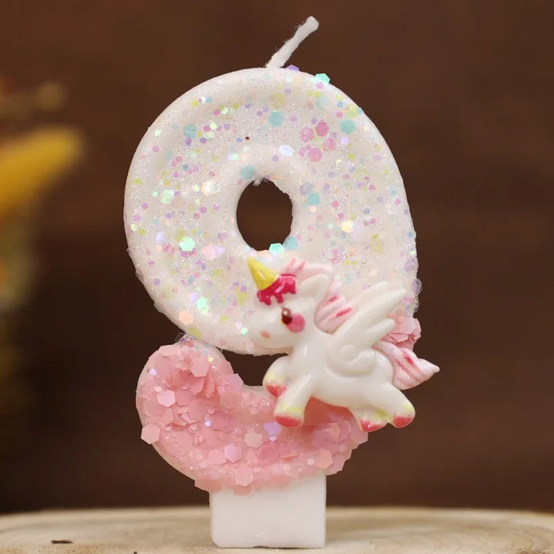 Una vela número cero blanca decorada con purpurina rosa y un acento en forma de corazón rosa.