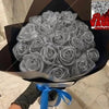 A bouquet of artificial roses covered in glitter is displayed in a black box with a blue ribbon.