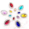 A collection of various colored gemstones, including red, blue, green, and yellow, set in flatback rhinestones.