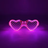 Pink herzförmige LED-Partybrille leuchtet hell vor dunklem Lila-Hintergrund