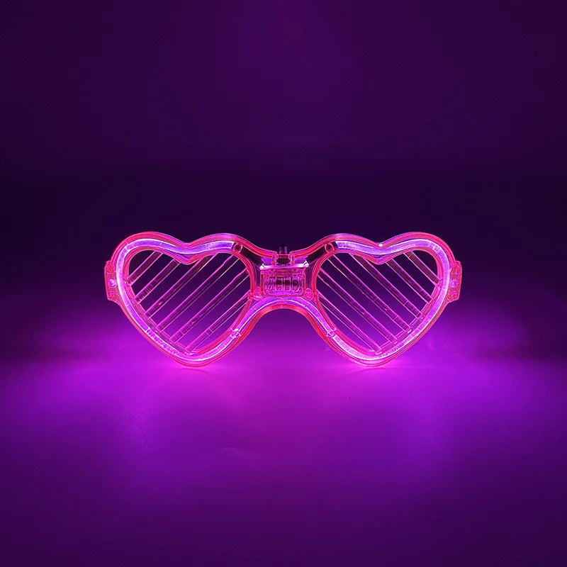 Pink herzförmige LED-Partybrille leuchtet hell vor dunklem Lila-Hintergrund