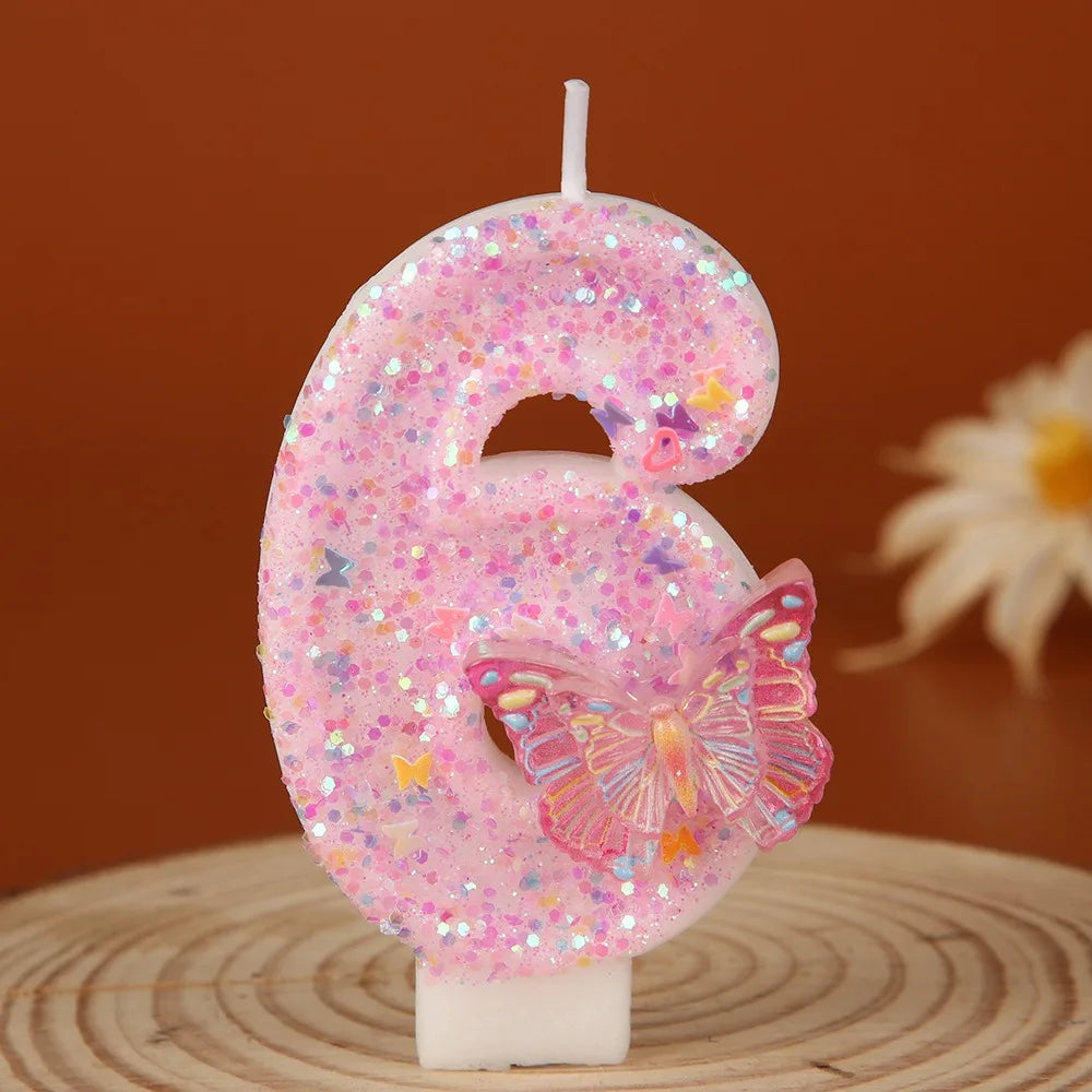 A pink glitter number six candle decorated with a butterfly on a white stick.
