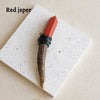 A reddish-orange crystal scepter wand with a dark handle rests on a white square surface.