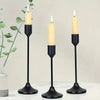 A set of three black minimalist retro tabletop candle holders with white taper candles on a white surface.