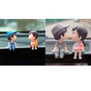 A set of cute couple figurines with balloons displayed on a car dashboard.