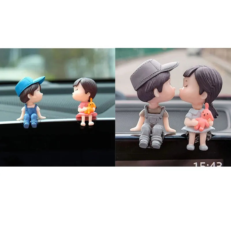 A set of cute couple figurines with balloons displayed on a car dashboard.