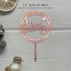 A rose gold acrylic cake topper set with a happy birthday message and a decorative stick on a light gray wooden surface.