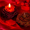 Nahaufnahme einer roten Kerze und einer glitzernden rosenförmigen Kerze auf rohem Seidenstoff.