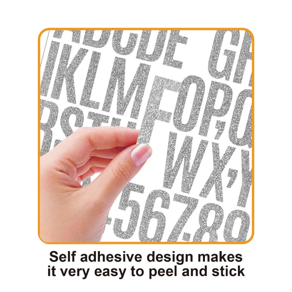 A hand is peeling and sticking glitter alphabet letter stickers onto a surface.