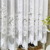 White lace mesh sheer curtain with rod pocket hanging in a vertical drape.