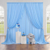 A light blue fabric party backdrop featuring draped curtains and a baby elephant figurine.