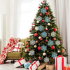 A decorated Christmas tree adorned with shimmering blue snowflake ornaments and red berries, set against a bright window.