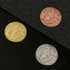 Tres monedas conmemorativas de metal, incluyendo variedades de oro y plata, exhibidas sobre una superficie negra.