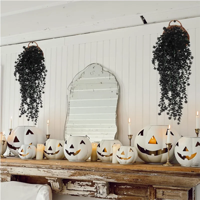 A display of carved pumpkin decorations and artificial black vine hanging plants on a rustic wooden surface.