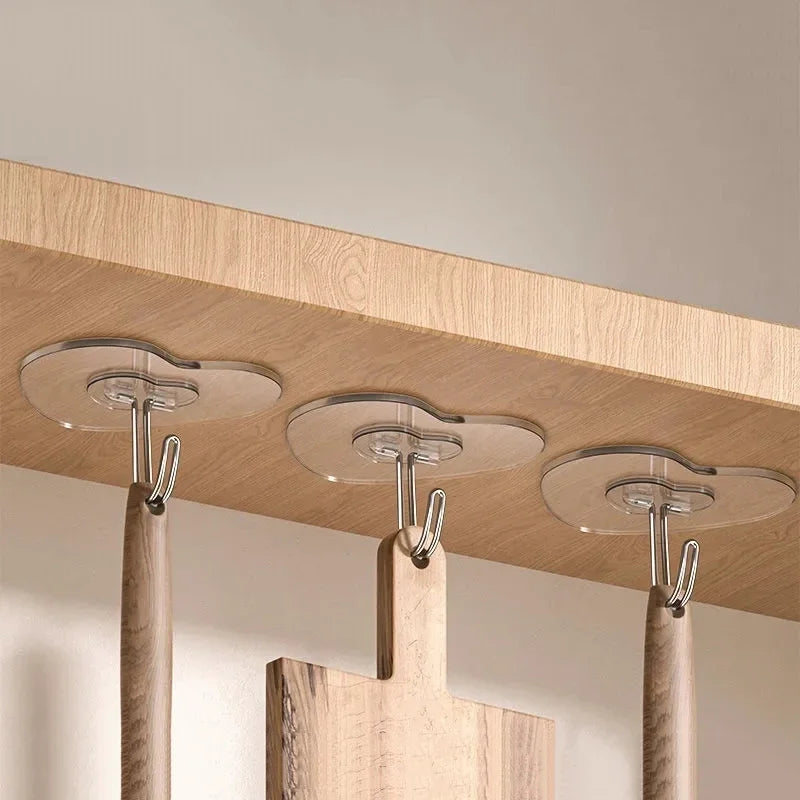 A close-up view of wooden hooks with clear, self-adhesive silicone hooks mounted on a light wood panel.