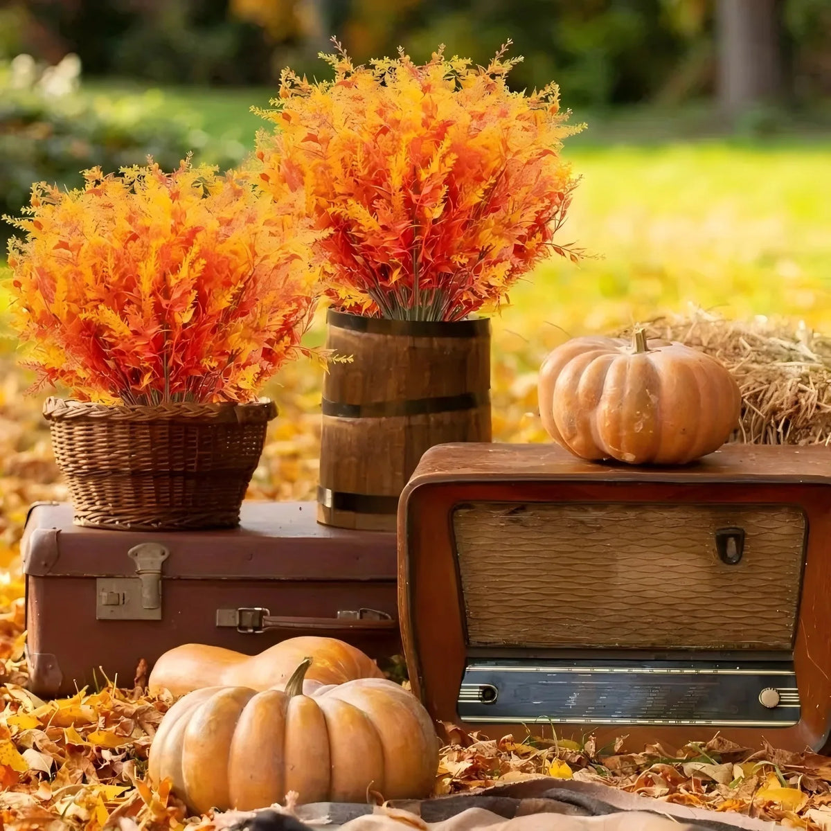 Artificial lavender stems in a terracotta pot surrounded by autumn foliage and pumpkins.