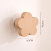 A light wood decorative animal hook with a flower shape mounted on a clear circular base.