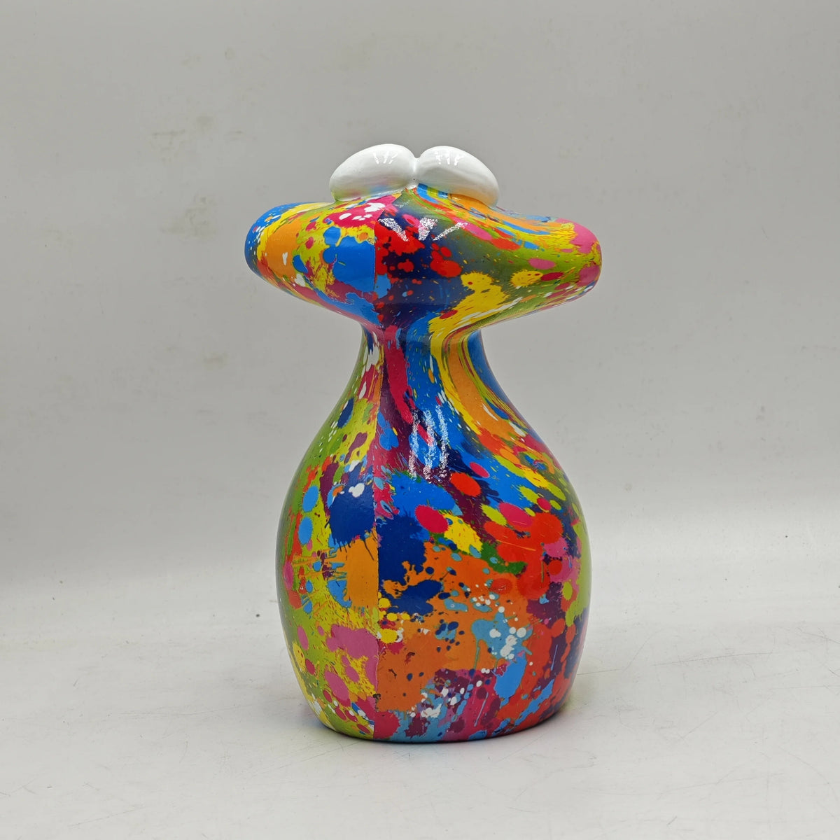 A colorful resin figurine of a frog with white eyes, painted in bright yellow, blue, orange, and red hues.