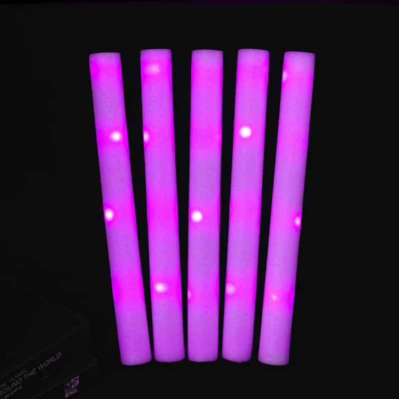Five vertical glow foam sticks in bright pink light against a dark background.