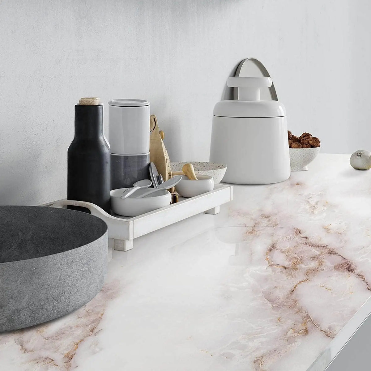 Una colección de utensilios de cocina de cerámica blanca y negra y un dispensador de vidrio blanco sobre una encimera de márm