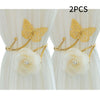 A set of two gold-colored decorative flower butterfly curtain tiebacks with white roses.