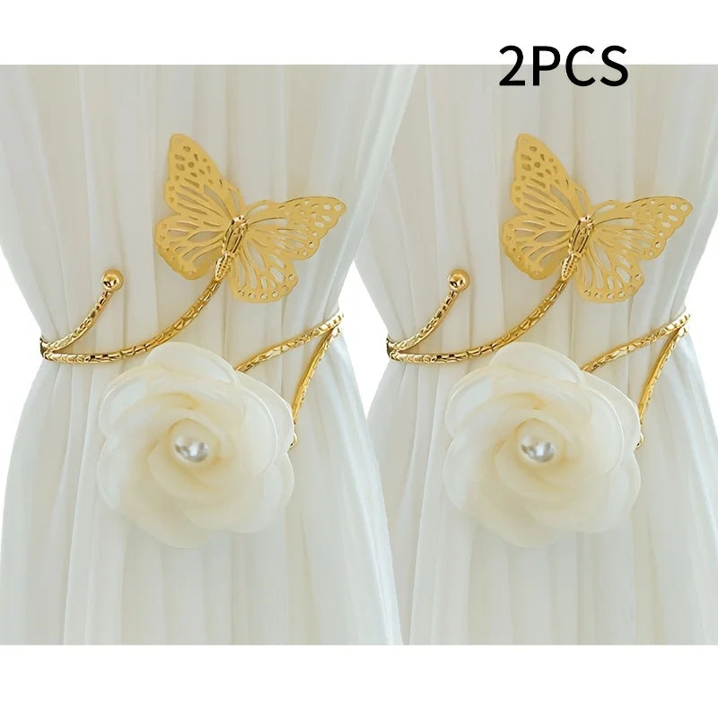 A set of two gold-colored decorative flower butterfly curtain tiebacks with white roses.