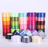 A collection of rolled silk satin ribbon in various shades of green, pink, orange, and purple.