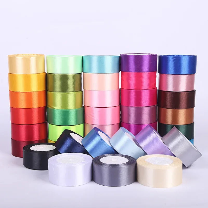A collection of rolled silk satin ribbon in various shades of green, pink, orange, and purple.
