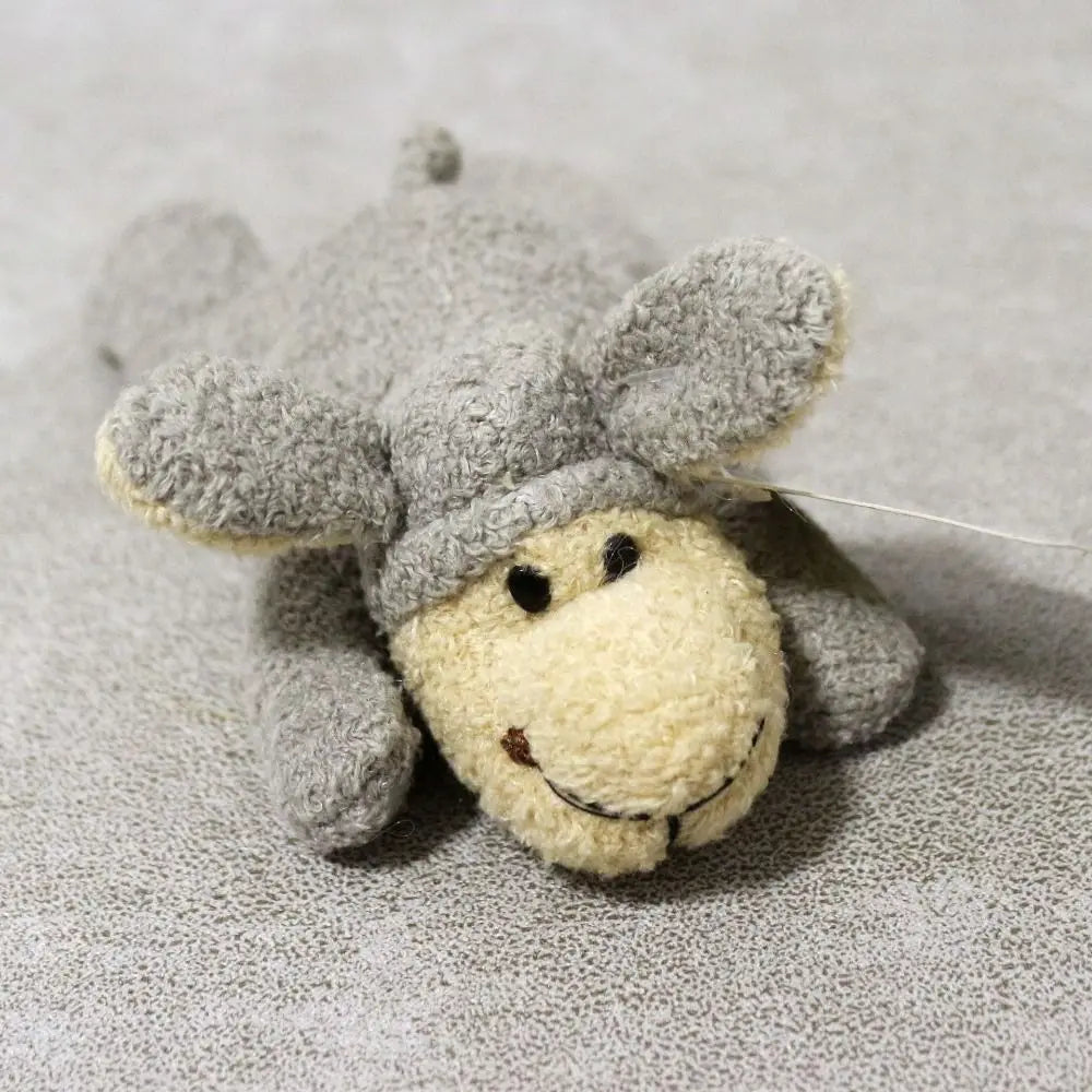 A small, gray plush animal with a yellow face is shown against a light gray background.