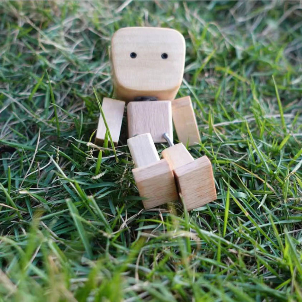 Figurine de bois sculptée à la main avec un visage et plusieurs petits blocs sur l'herbe verte.
