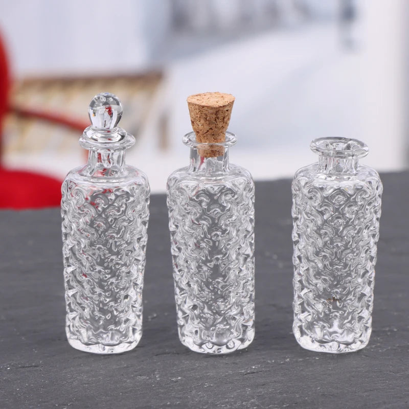 A set of three clear glass bottles and a cork stopper displayed on a dark surface.