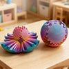 A colorful 3D printed gear ball fidget spinner resting on a wooden table.