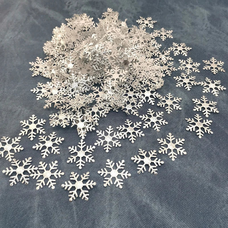 Silver frosted snowflake confetti scattered on a dark blue fabric.
