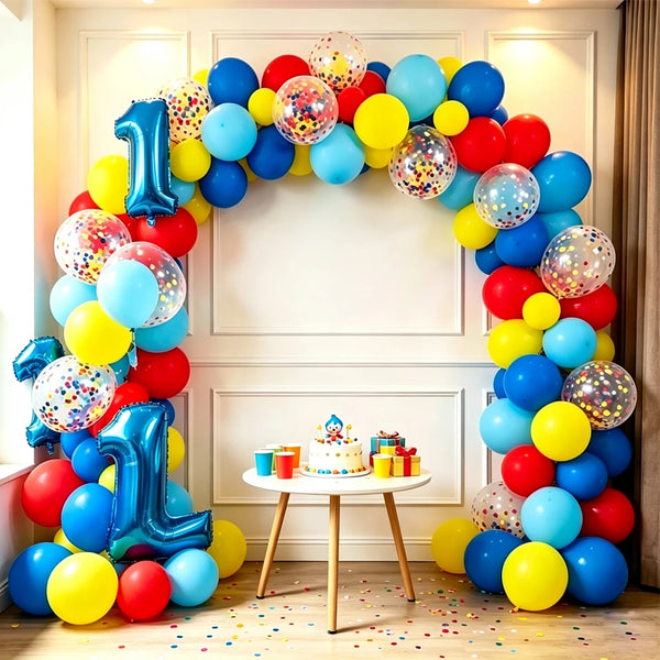 A colorful arch garland made of balloons in blue, yellow, and red surrounds a white wall for a party decoration.