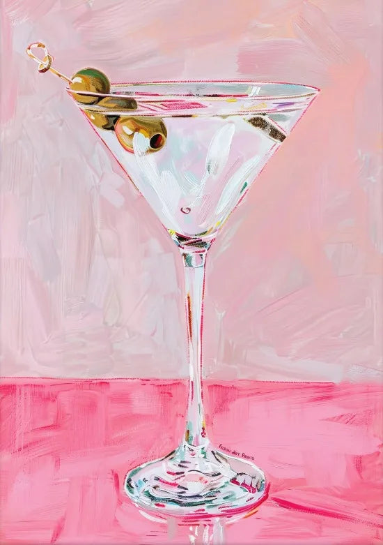 A pink-tinted glass cocktail with olives garnishing the rim, set on a pink surface.