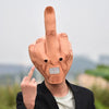 A person wearing a latex finger mask shaped like a middle finger, with a silver grid mouth, is shown holding up a finger.