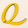 A bright yellow 3D acrylic letter Q with black outline against a light background.