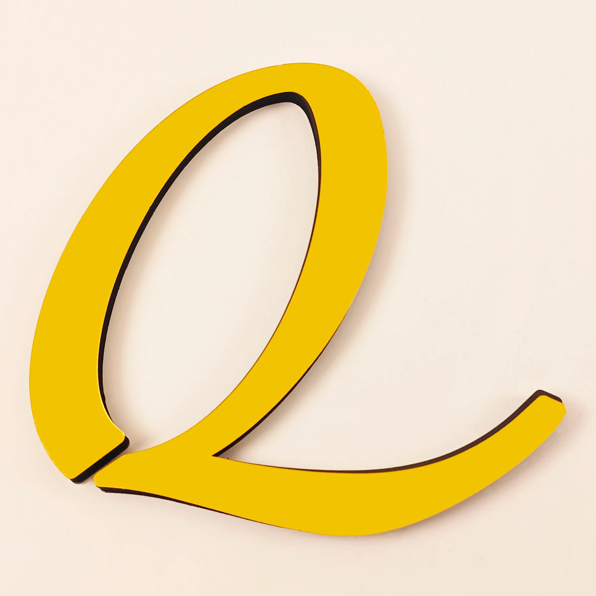 A bright yellow 3D acrylic letter Q with black outline against a light background.