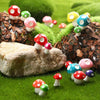 A collection of colorful resin mini mushroom figurines scattered on green grass and rocks.